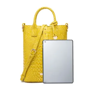 Bolso de mano amarillo con grabado de cocodrilo mostrado con una tablet de guía