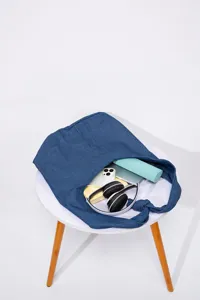 Bolso tote grande de lona vaquera azul que muestra artículos como auriculares y móvil