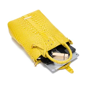 Vista detallada del bolso amarillo con grabado de cocodrilo mostrando su capacidad