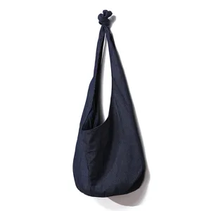 Detalle de un bolso bandolera vintage de lino azul oscuro con un nudo en el asa.