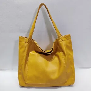 Vista frontal de un bolso tote amarillo grande de cuero con bolsillo externo