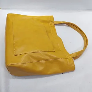 Vista lateral del bolso tote de cuero encerado amarillo con bolsillo frontal grande