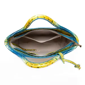 Detalle de bolso de mano con patrón de cocodrilo azul y amarillo que muestra el interior.