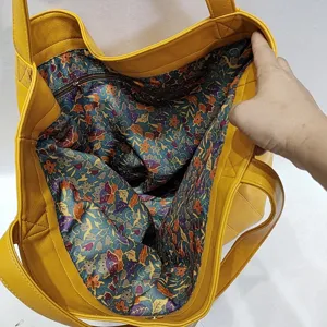 Detalle del forro floral y el bolsillo interior con cremallera del bolso tote amarillo.
