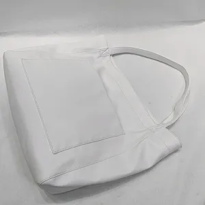 Vista detallada del bolso tote grande blanco de piel suave con un bolsillo exterior.