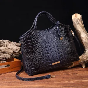 Vista detallada del bolso de mano azul marino con relieve de cocodrilo y herrajes oro