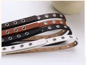 Detail of women's punk style faux leather belts with all-over silver metal eyelets.