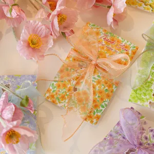 Close-up detail of floral thank you card featuring a delicate orange organza ribbon bow