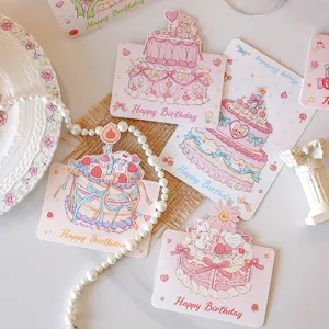 Close-up detail of cute birthday greeting cards featuring pastel cake illustrations and pearls.