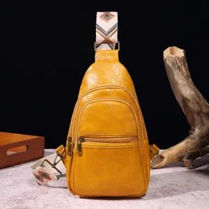 Primer plano de bolso bandolera de cuero sintético amarillo con correa bohemia.