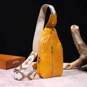 Detalle de un bolso bandolera vintage amarillo mostaza con una correa ancha estilo boho