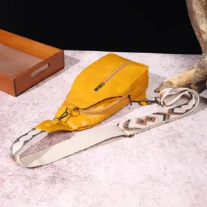 Vista detallada del bolso bandolera vintage amarillo con correa boho estampada.