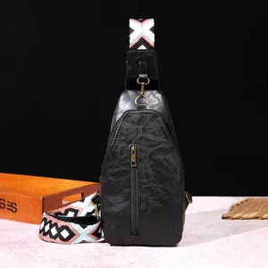 Detalle de bolso de pecho negro vintage en cuero con correa con estampado bohemio.