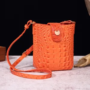 Primer plano de un bolso bandolera naranja vibrante con textura de piel de cocodrilo