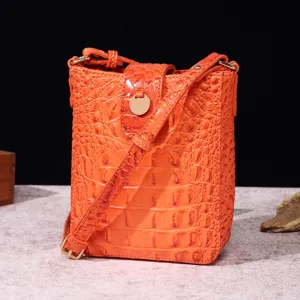 Detalle del relieve de cocodrilo naranja en un elegante bolso bandolera para móvil.