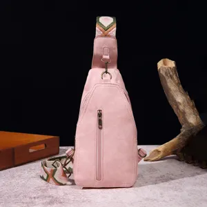 Detalle de bolso de pecho vintage rosa con correa ancha estilo bohemio