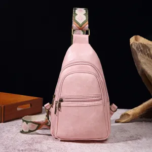 Vista detallada de un bolso de pecho rosa vintage con correa bohemia.