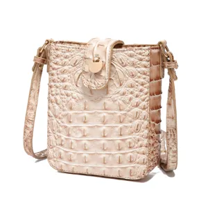 Vista detallada del mini bolso bandolera crema con grabado de cocodrilo y cierre dorado
