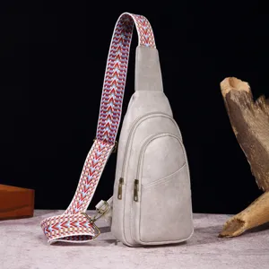 Detalle de un bolso de pecho retro gris con una colorida correa tejida bohemia