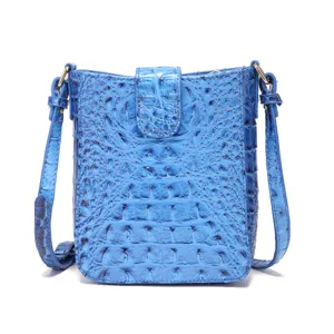 Detalle de un bolso bandolera azul brillante con textura de patrón de cocodrilo vintage.