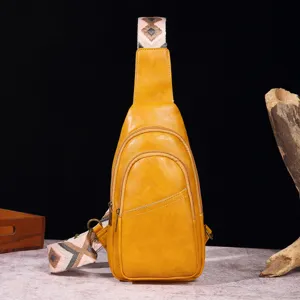 Vista frontal de bolso bandolera de cuero amarillo con correa bohemia sobre fondo oscuro