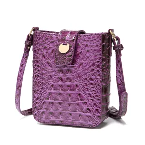 Detalle de bolso bandolera morado con estampado de cocodrilo y hebilla metálica dorada.