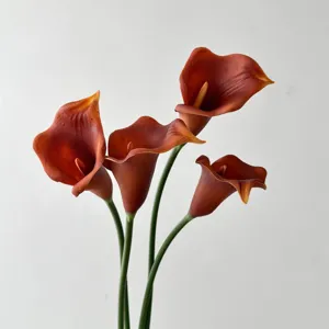 Vue détaillée de quatre lys calla artificiels en PU orange pour la déco
