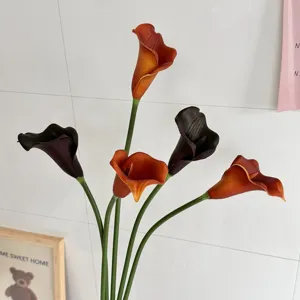 Gros plan sur des lys calla en PU orange et noirs réalistes pour décoration chic.