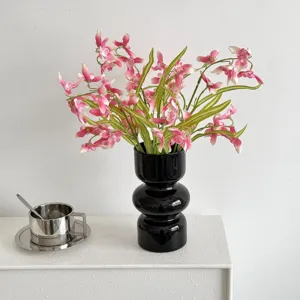 Pink and white artificial cymbidium orchids in a modern black gourd-shaped vase