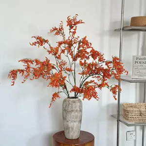 Ramas vibrantes de orquídeas artificiales naranjas en un jarrón cerámico rústico decor