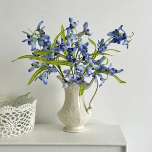 Elegant artificial blue orchid flower arrangement in a cream textured ceramic vase