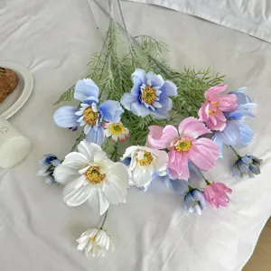 Detailed view of pink blue and white artificial cosmos flowers on soft white fabric