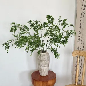 Primer plano de hierba verde artificial en un jarrón de cerámica para decoración hogar.