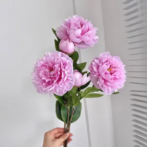 Realistic pink artificial silk peony flower bouquet with green leaves close-up view