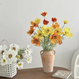 Vibrant 4-head artificial cosmos flowers in terracotta vase for living room decor.