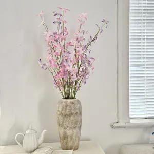 Detail of pink artificial Oncidium orchid flowers in a rustic vase for home decoration