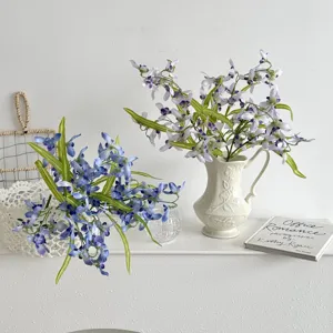 Detailed view of small blue and purple artificial vanda orchid flowers in a white vase.
