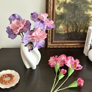 Close-up of oil painting style artificial purple and pink iris flowers in a modern white vase