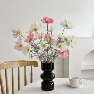 Macro detail of elegant pink and white artificial cosmos flowers in a tiered black vase