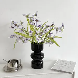 Detail of realistic purple orchids in a black vase for home decor and lifestyle styling