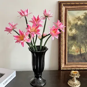 Realistische roze kunstmatige cactusbloemen in een zwarte vaas op een houten tafel