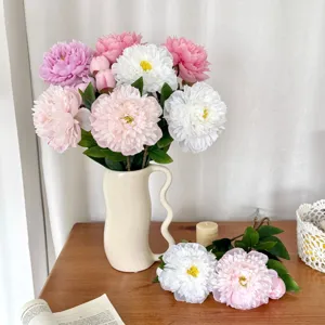 Elegant artificial peony bouquet in a cream ceramic vase on a wooden table for home decor