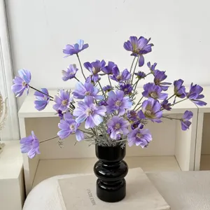 Purple artificial cosmos flowers in a black ceramic vase on a white shelf for home decor