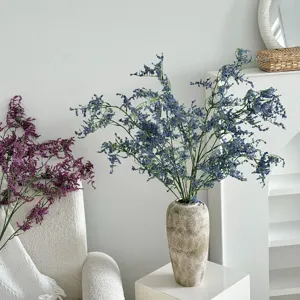 Vista detallada de flores de estátice azules artificiales realistas en un jarrón rugoso