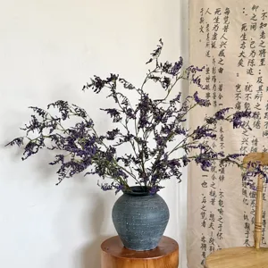 Vista detallada de flores de statice artificiales moradas en un jarrón gris rústico