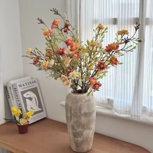 Detailed view of autumn-toned artificial wild chrysanthemums displayed in a rustic tall vase