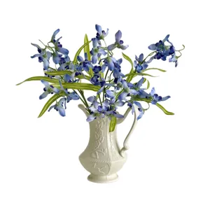 Elegant blue artificial orchid flower arrangement in a decorative white ceramic vase