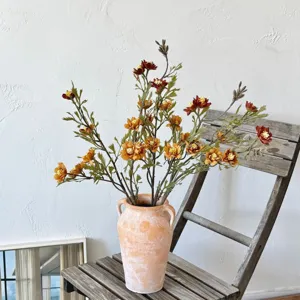 Detailed shot of autumn orange artificial daisies in a rustic vase on a wooden chair