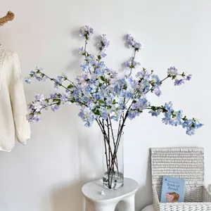 Kunstmatige blauwe kersenbloesemtakken in een glazen vaas voor huisdecoratie in huis