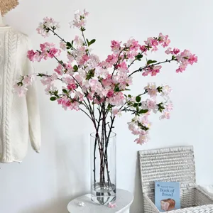 Close-up van roze kunstmatige kersenbloesemtakken in een hoge glazen vaas voor decor